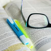 解析编辑部内容编辑在窗边阅读打印材料并用荧光笔标注，暖阳照在纸页上